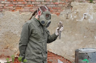 Gaz maskesi ve yeşil askeri giysileri ile adam ölü kuş kimyasal felaketinden sonra araştırıyor..