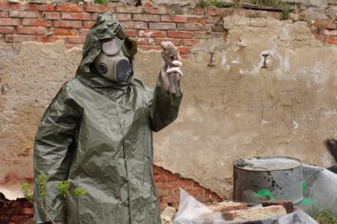 Gaz maskesi ve yeşil askeri giysileri ile adam ölü kuş kimyasal felaketinden sonra araştırıyor..