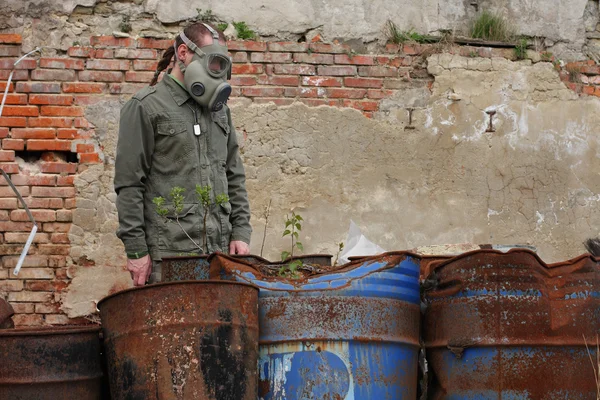 Homme avec masque à gaz et vêtements militaires verts explore petite usine après une catastrophe chimique . — Photo