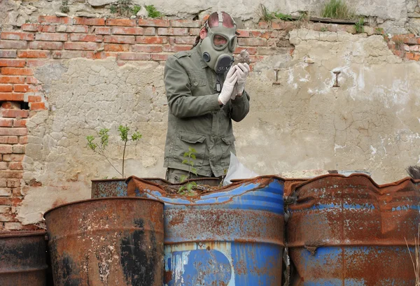 Homme avec masque à gaz et vêtements militaires verts explore oiseau mort après une catastrophe chimique . — Photo