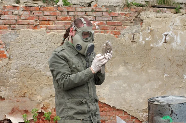 Homme avec masque à gaz et vêtements militaires verts explore oiseau mort après une catastrophe chimique . — Photo