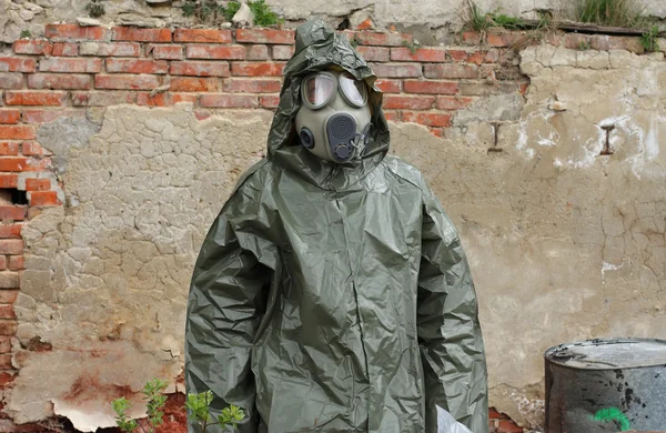 Homme avec masque à gaz et vêtements militaires verts explore petite usine après une catastrophe chimique . — Photo