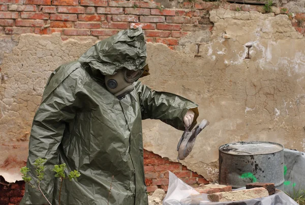 Homme avec masque à gaz et vêtements militaires verts explore oiseau mort après une catastrophe chimique . — Photo