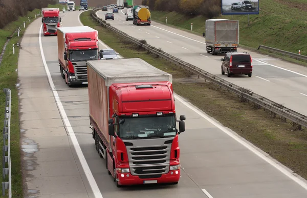 Drie rode vrachtwagens op de snelweg — Stockfoto