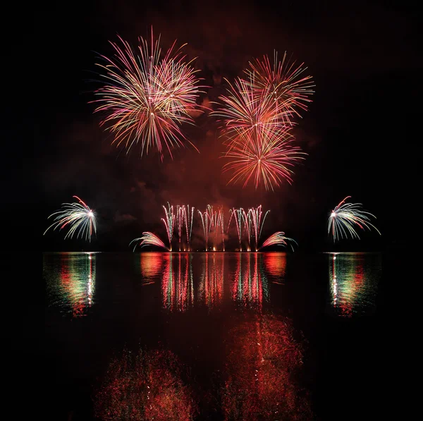 Färgglada fyrverkerier med reflektion på sjön. — Stockfoto
