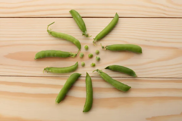 Guisantes verdes y vainas de guisantes en mesa de madera — Foto de Stock