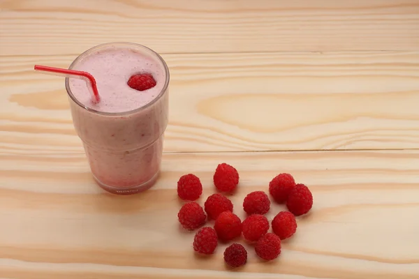 Batido de frambuesas en un vaso y frambuesas en madera —  Fotos de Stock