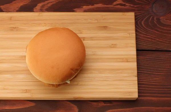 Куриный бургер на бамбуковой доске на деревянном столе — стоковое фото