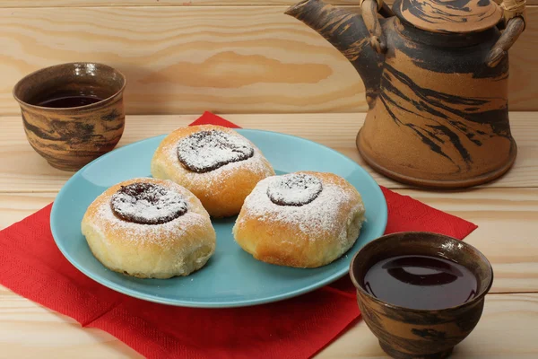 Творожные пирожные с джемом на голубой тарелке и чайный сервиз — стоковое фото