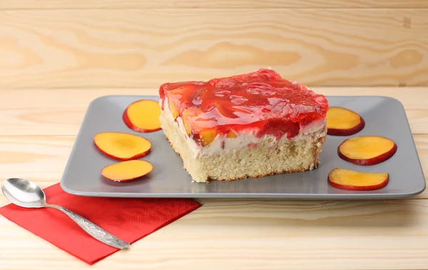 Strawberry and peach cake with gelatin on grey plate on wooden t — Stock Photo, Image