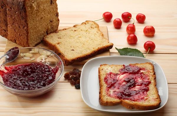 Süßes Brot mit Rosinen und Mandeln, Butter und Kirschmarmelade — Stockfoto