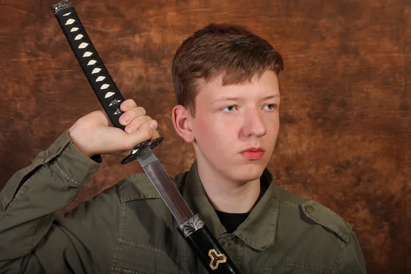 Hombre con espada katana sobre fondo batik marrón —  Fotos de Stock