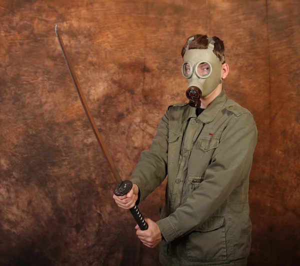 Hombre con máscara de gas y espada katana sobre fondo batik marrón — Foto de Stock