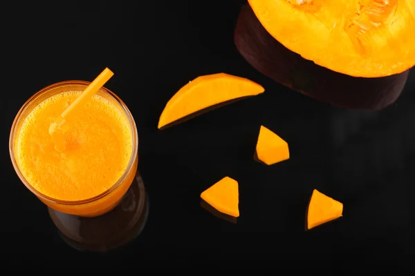 Pumpkin smoothie in glass and pieces of pumpkin  on black — Stock Photo, Image