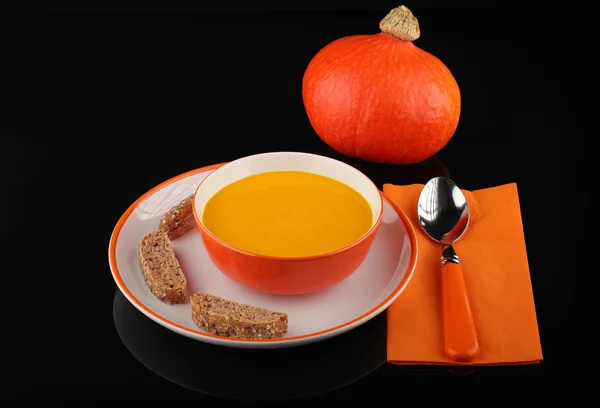 Bowl of pumpkin hokkaido soup with bread  on  black — Stock Photo, Image