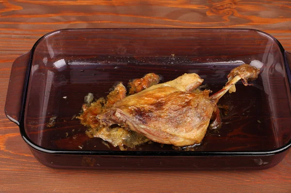 Roast duck in glass pan on wooden table — Stock Photo, Image