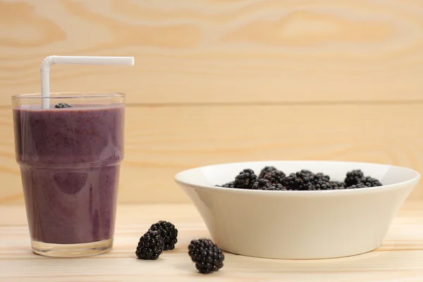 El batido de las moras en el vaso y las moras sobre la madera —  Fotos de Stock