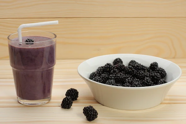 El batido de las moras en el vaso y las moras sobre la madera —  Fotos de Stock