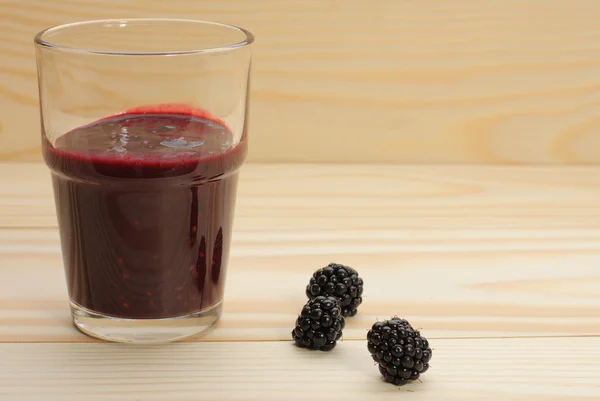 El batido de las moras en el vaso y las moras sobre la madera —  Fotos de Stock