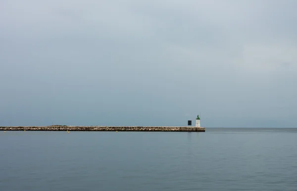 Faro en el muelle, sobre el fondo cielo nublado . — Foto de Stock