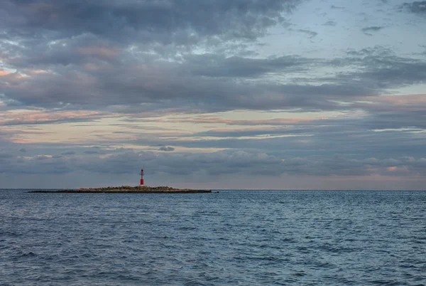 Faro rojo en pequeña isla, sobre el fondo cielo nublado . — Foto de Stock