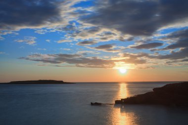 Bulutlar deniz seviyesinden arkasında güneşte günbatımı zamanı