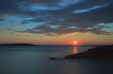 Bulutlar deniz seviyesinden arkasında güneşte günbatımı zamanı