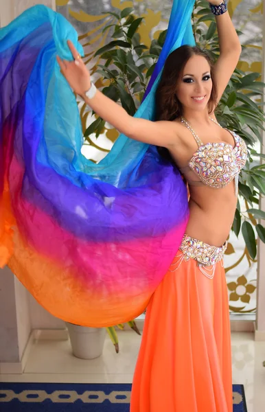 Beautiful brunette, belly dancer with rainbow shawl in the arabic harem interior — Stock Photo, Image