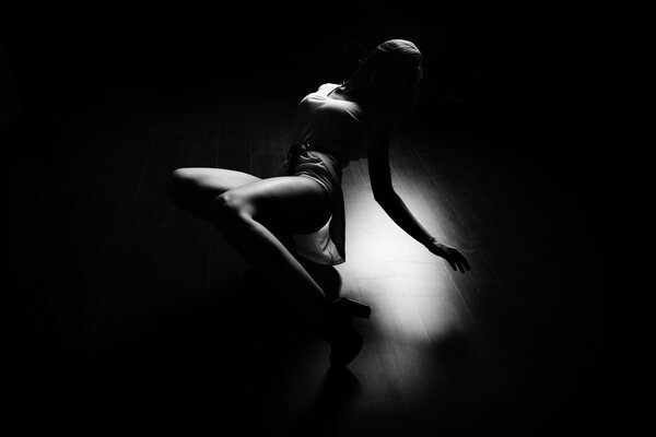 Brunette sexy slim woman laying dancing on floor, indoors, black and white