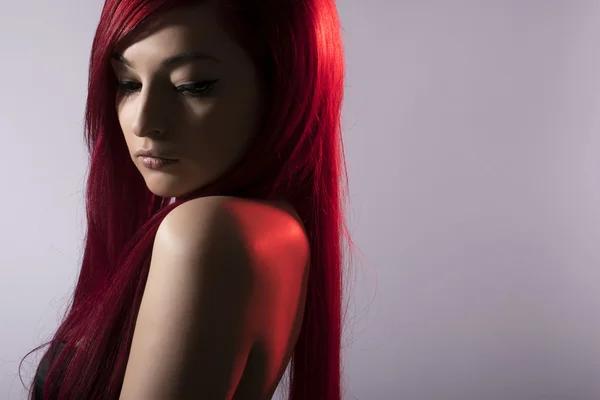 Beautiful red haired woman posing over grey background — Stock Photo, Image