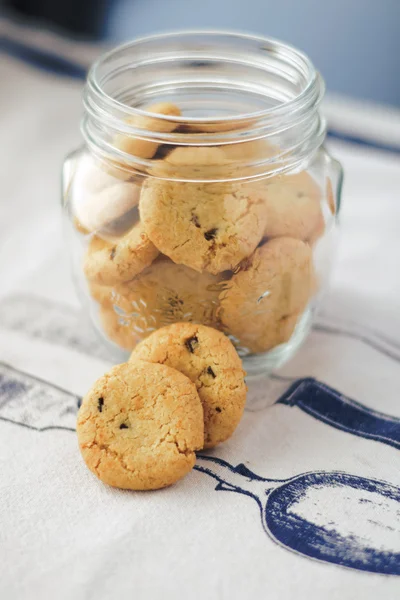 Cookies in glass jar on white napkin in the kitchen — Stock Photo, Image