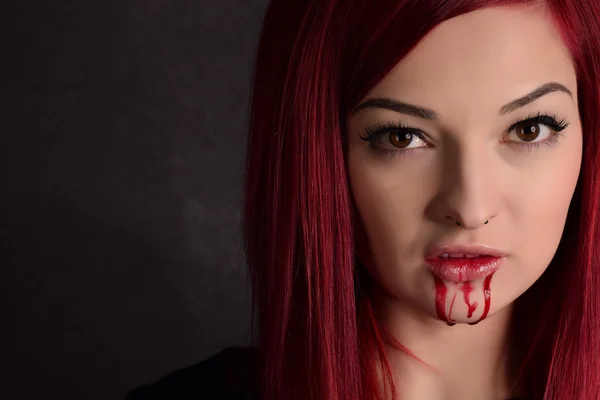 Женщина-вампир с кровью на лице и рыжими волосами — стоковое фото