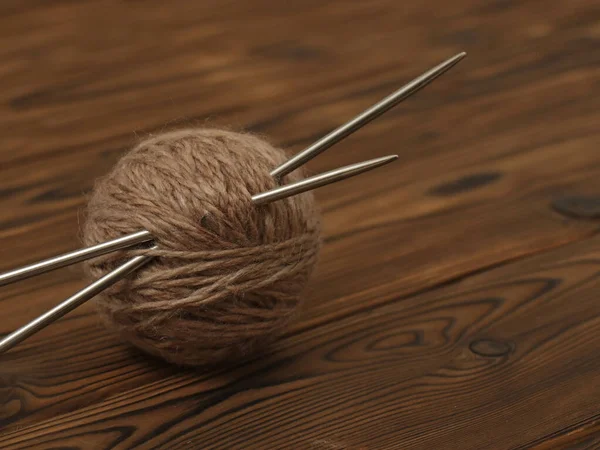 茶色のテーブルの上にベージュのウールボールと編み物針 — ストック写真