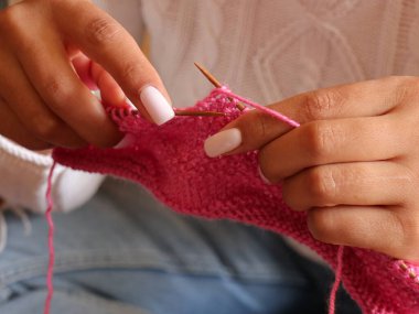 Kadın ellerini pembe örgü kumaş ve iğnelerle kapat.