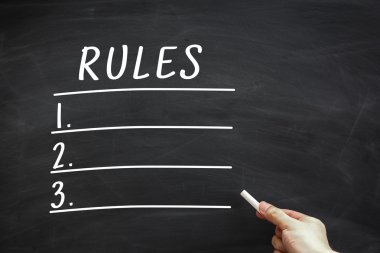 Kural listesine tahtaya bir kenara Beyaz tebeşir tutan el ile yazılmış.