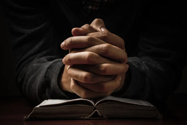 Betende Hände mit der Bibel Stockbild