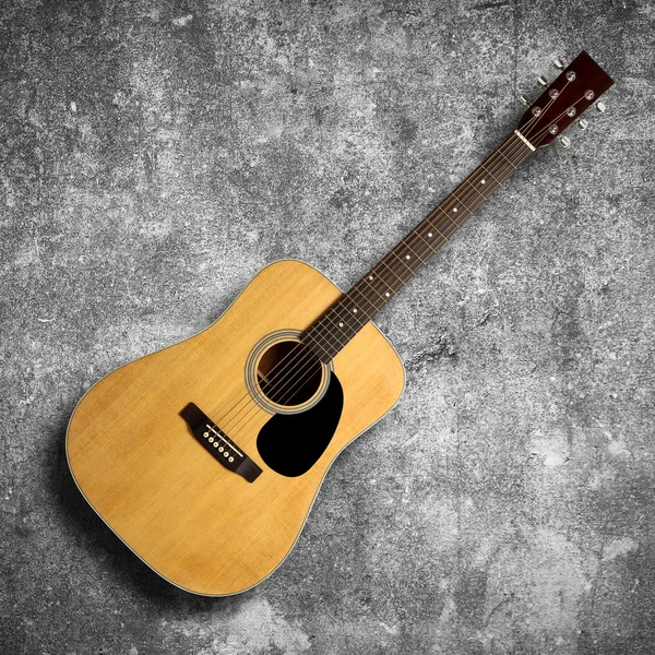 Акустическая гитара на серой стене — стоковое фото