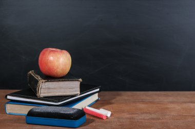 Apple, kitap ve tahta arka plan ile tebeşirler