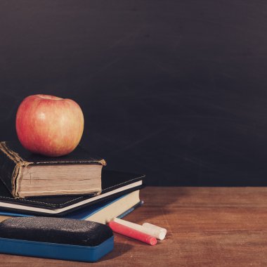 Apple, kitap ve tahta arka plan ile tebeşirler