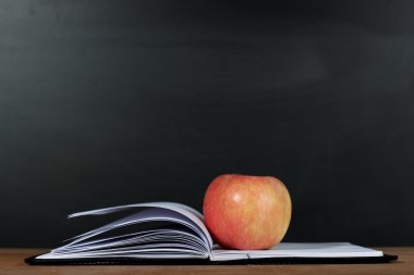 Elma ve tahta arka plan ile açık kitap
