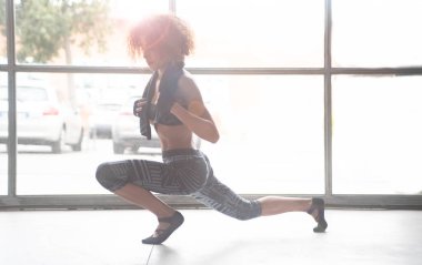 Genç ve güzel bir kadın spor salonunun zemininde egzersiz yaptıktan sonra geriniyor. Yatay