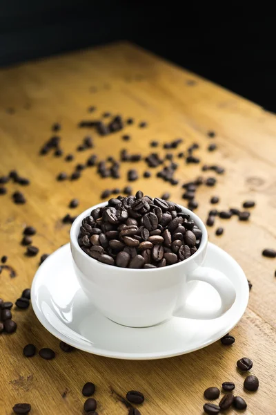 Fincan kahve çekirdekleri masada dolu — Stok fotoğraf