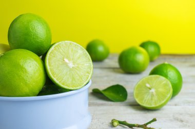 sarı arka plana sahip ahşap masa üzerinde yeşil limon