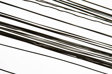 Silüet düzensizliği, beyaz arka planda izole edilmiş siyah elektrik kablolarının dağınık çizgisi. Gökyüzü arkaplanlı sayısız kaotik elektrik telefon kablosu. Elektrik ve iletişim kavramı