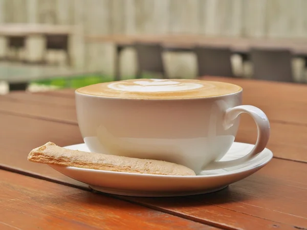 White cup of coffee and biscuit with blur background — Stock Photo, Image