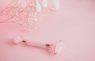 Yüzünde pembe doğal yeşim taşıyla kuvars silindirli masaj. Gouache masaj aleti, güzellik serumu yağı ile. Evde yaşlanma ve kaldırma karşıtı. Yüz masajı ve rahatlama konsepti.