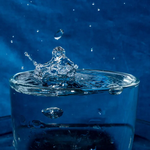 Nyckfull stänk droppar i ett glas vatten Royaltyfria Stockbilder
