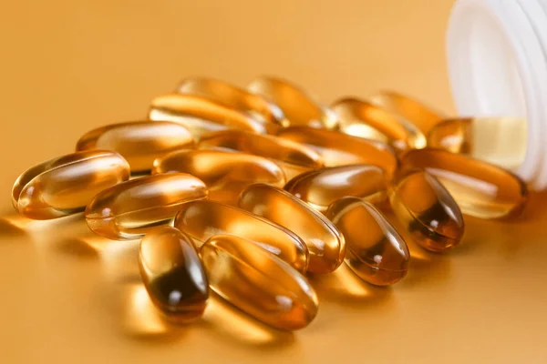 Sarı arka planda birçok Omega 3 kapsülü var. Yakın çekim, yüksek çözünürlüklü ürün. Sağlık hizmeti kavramı.