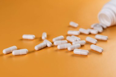 Eczacılık ilaçları beyaz haplar, tabletler veya sarı arka planda kapsüller..