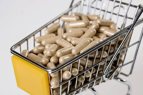 Tam bir ilaç arabası, beyaz arka planda ilaç kapsülleri. Sağlık hizmeti kavramı.